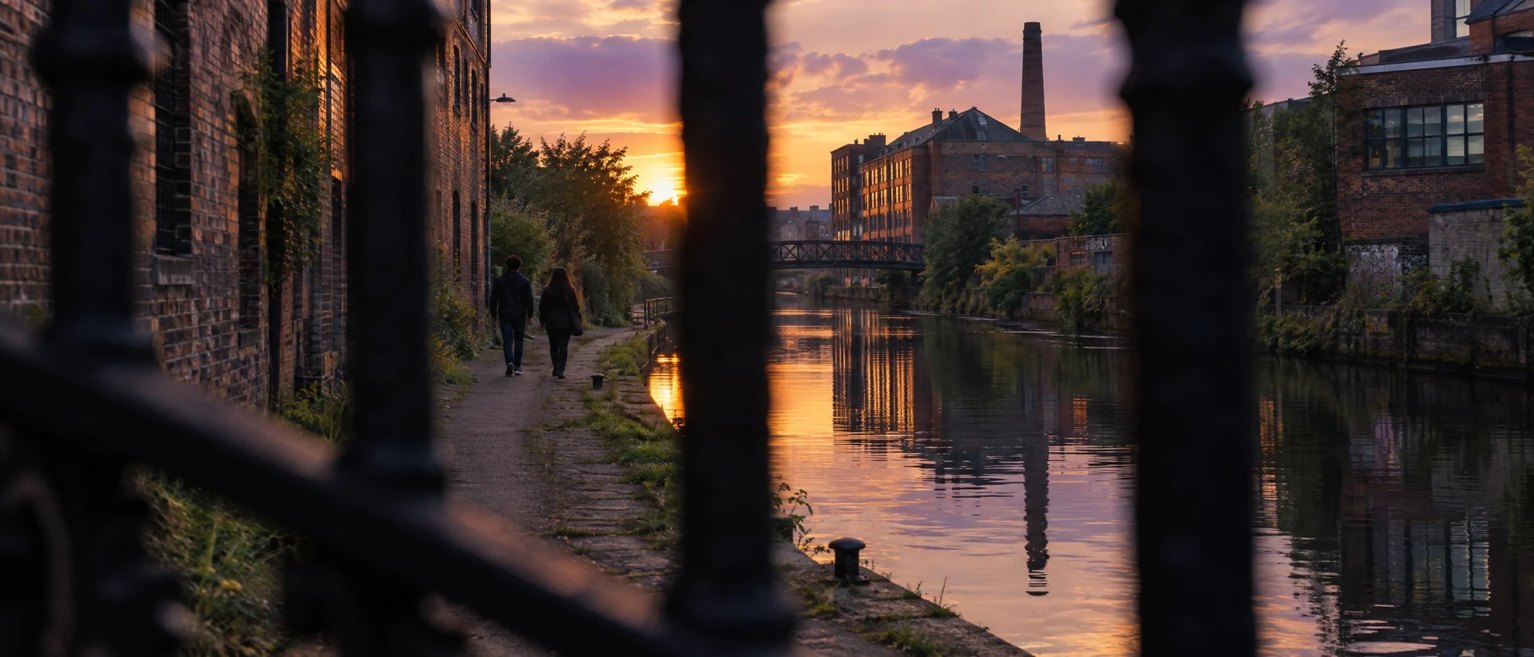 A Birmingham canal at the end of a summer day, seen through railings